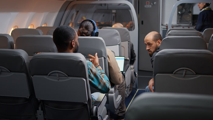 Airplane passengers in rows, discussing window seat issue with expressions of annoyance and determination. Airplane passengers in rows, discussing window seat issue with expressions of annoyance and determination.