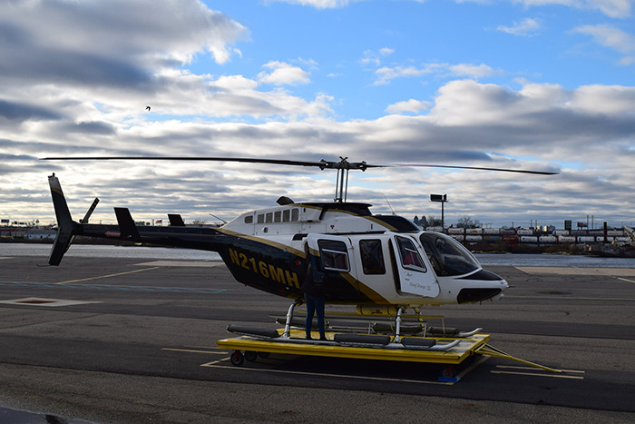 Helicopter on runway with pre-flight inspection by pilot under cloudy sky. Helicopter on runway with pre-flight inspection by pilot under cloudy sky.