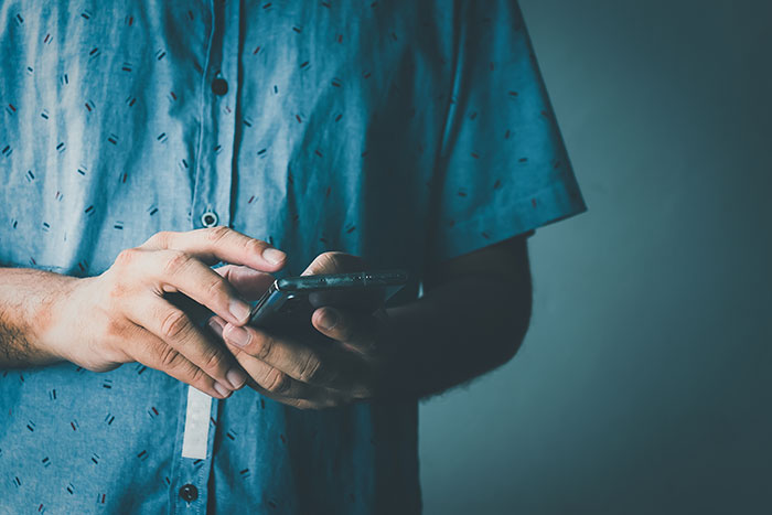 Man in a casual shirt texting on a smartphone, focused on the screen. Man in a casual shirt texting on a smartphone, focused on the screen.
