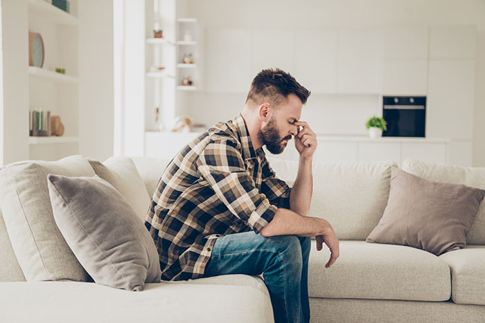 Man sitting on a sofa looking stressed about babysitting situation. Man sitting on a sofa looking stressed about babysitting situation.
