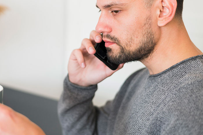 Man talking on phone, concerned expression, holding a mug, addressing babysitting and disappearance issue. Man talking on phone, concerned expression, holding a mug, addressing babysitting and disappearance issue.