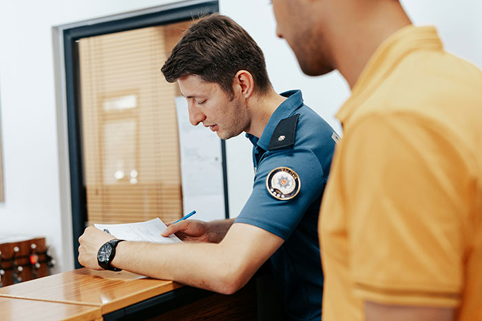 Police officer and man in a yellow shirt discussing a missing person report. Police officer and man in a yellow shirt discussing a missing person report.
