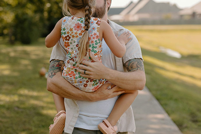 Man holding a young girl outdoors, focusing on the theme of babysitting. Man holding a young girl outdoors, focusing on the theme of babysitting.