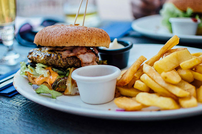 Burger and fries on a plate, paired with dipping sauces, symbolizing dietary challenge during birthday plans. Burger and fries on a plate, paired with dipping sauces, symbolizing dietary challenge during birthday plans.