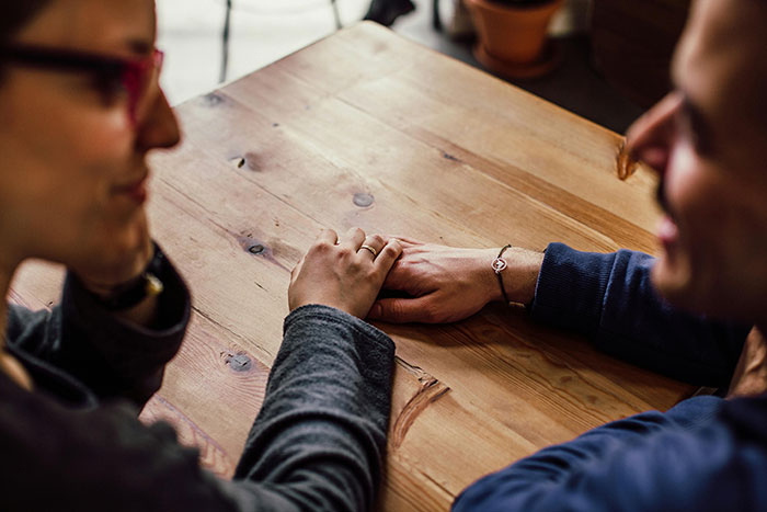 Two friends discussing birthday plans at a wooden table, one wearing a bracelet, focusing on a diet conversation. Two friends discussing birthday plans at a wooden table, one wearing a bracelet, focusing on a diet conversation.