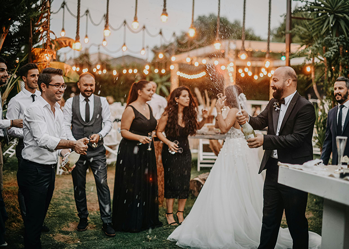 Guests celebrating with champagne at a wedding reception outdoors, under string lights. Guests celebrating with champagne at a wedding reception outdoors, under string lights.