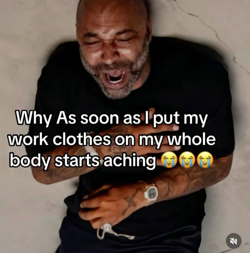 A man in a black shirt laughs with closed eyes, reclining while reading a humorous work-related meme.