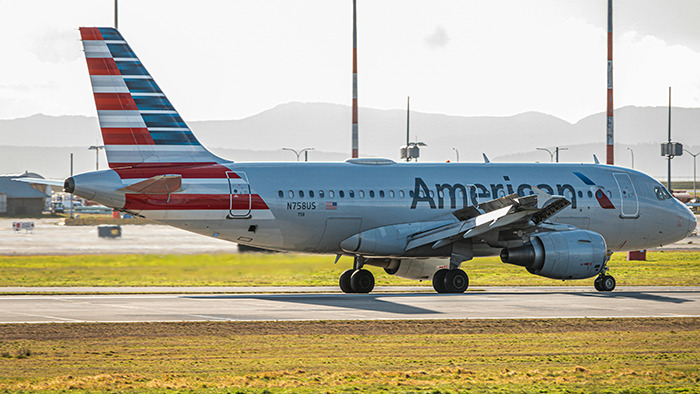 Airlines worker delivers speech amid delay; airplane on runway with mountains in background. Airlines worker delivers speech amid delay; airplane on runway with mountains in background.