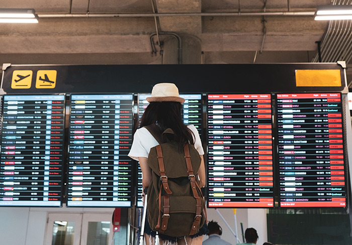 Airline passenger with backpack checks flight board amid travel delay. Airline passenger with backpack checks flight board amid travel delay.