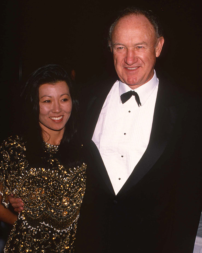 Man in a tuxedo and woman in a sequined dress smiling at an event, related to Gene Hackman handwritten notes discovery. Man in a tuxedo and woman in a sequined dress smiling at an event, related to Gene Hackman handwritten notes discovery.