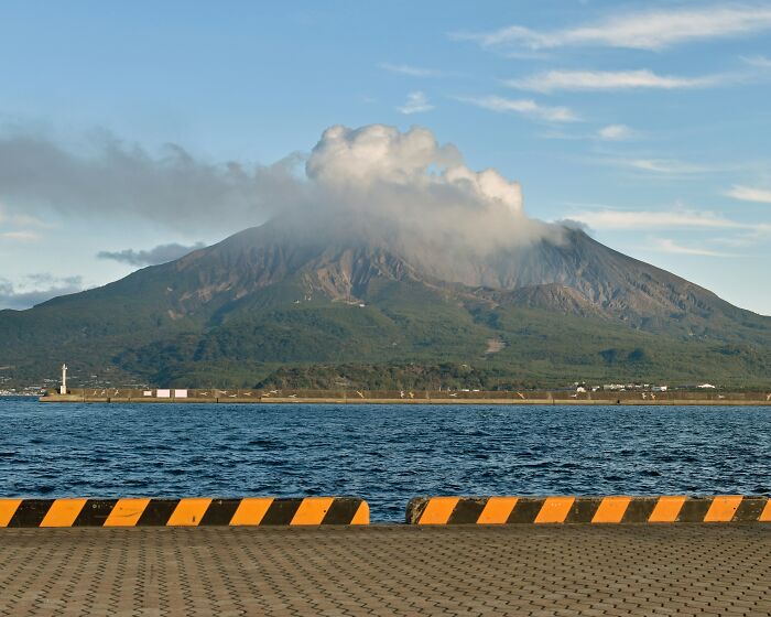 Volcanic mountain with clouds above and water in the foreground at a super normal thing country harbor area.