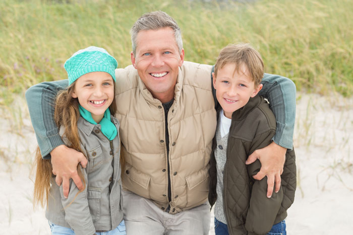 Smiling man with two children, representing a wholesome parent at the beach. Smiling man with two children, representing a wholesome parent at the beach.