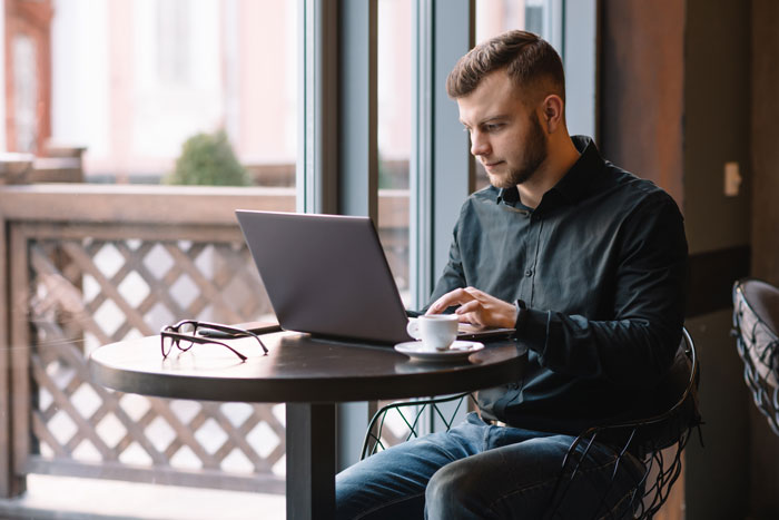 Man at a cafe working on a laptop, unaware of viral Reddit mod's double life. Man at a cafe working on a laptop, unaware of viral Reddit mod's double life.
