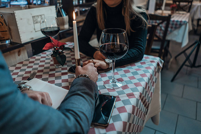 Couple holding hands at a romantic dinner with wine and a lit candle on a checkered tablecloth. Couple holding hands at a romantic dinner with wine and a lit candle on a checkered tablecloth.