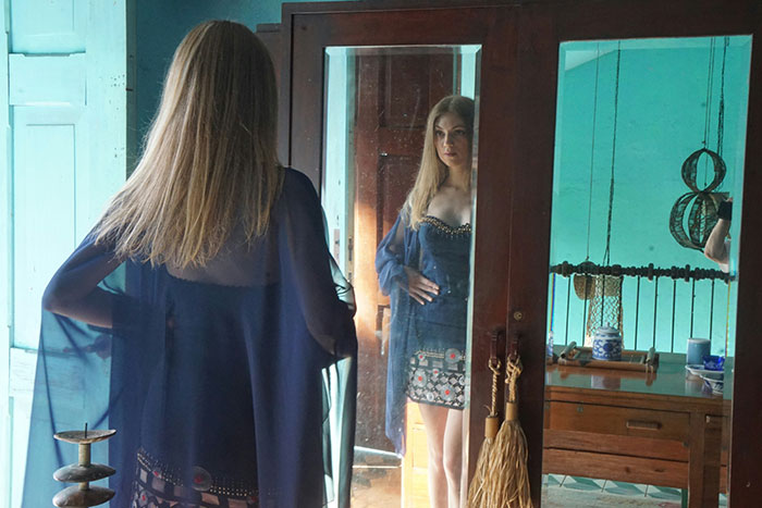Woman in a blue dress looks at her reflection in a mirror. Woman in a blue dress looks at her reflection in a mirror.