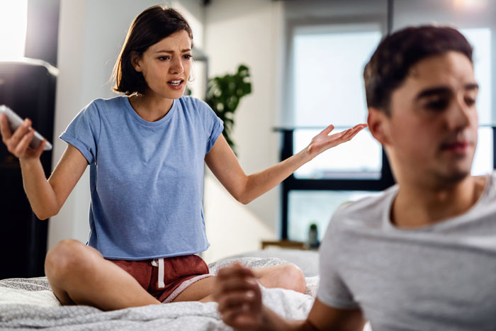 Woman in casual clothes arguing with a man on a bed, emphasizing disagreement and tension. Woman in casual clothes arguing with a man on a bed, emphasizing disagreement and tension.