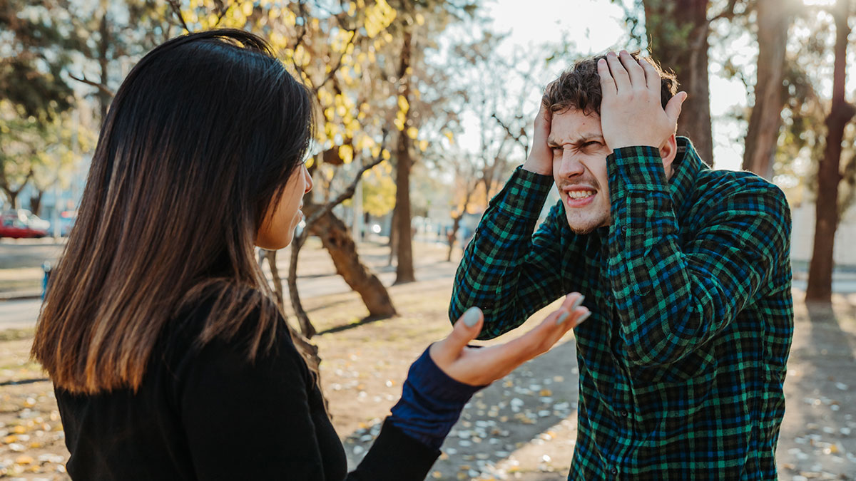 Couple arguing outside in autumn park, illustrating emotions related to things found in partner's phones by netizens.