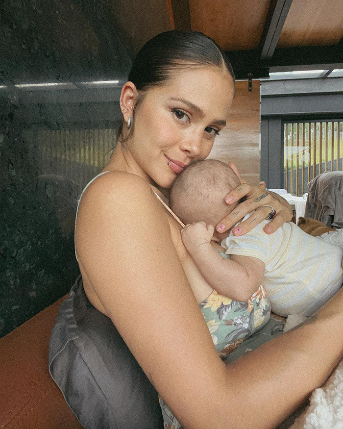 Singer Greeicy holding her baby close, showcasing a serene motherhood moment indoors. Singer Greeicy holding her baby close, showcasing a serene motherhood moment indoors.