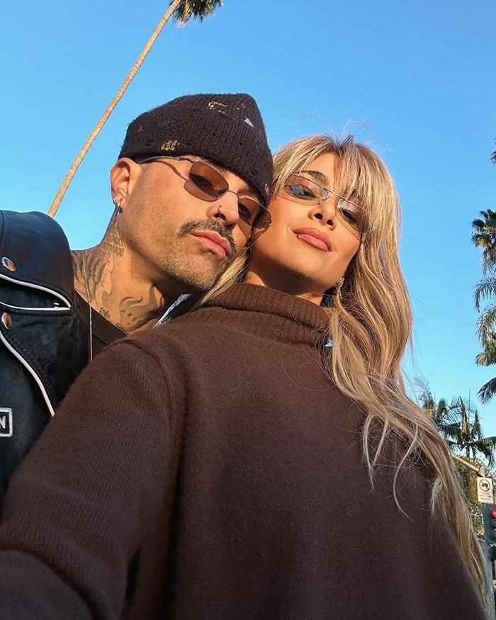 Two people in sunglasses under palm trees, blue sky, related to singer Greeicy's "husband stitch" revelation. Two people in sunglasses under palm trees, blue sky, related to singer Greeicy's "husband stitch" revelation.