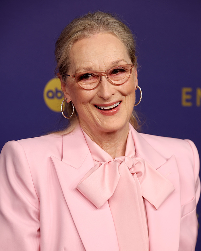 Woman in a pink blazer and glasses smiling at a Narnia reboot event. Woman in a pink blazer and glasses smiling at a Narnia reboot event.