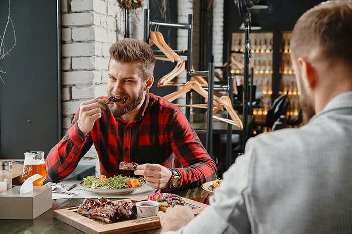 Man in a red flannel enjoying ribs at a restaurant, known for ordering more than friends during meals. Man in a red flannel enjoying ribs at a restaurant, known for ordering more than friends during meals.