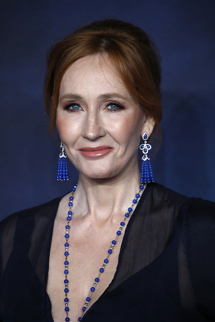 JK Rowling smiling at an event, wearing blue necklace and earrings, following trans ruling celebration. JK Rowling smiling at an event, wearing blue necklace and earrings, following trans ruling celebration.