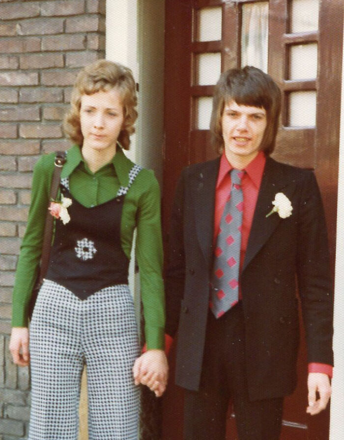 Vintage couple with unique hairstyles holding hands outside a building.