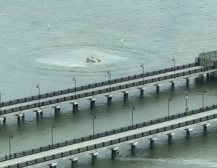 NYC helicopter crash site in water near a bridge, debris partially submerged. NYC helicopter crash site in water near a bridge, debris partially submerged.