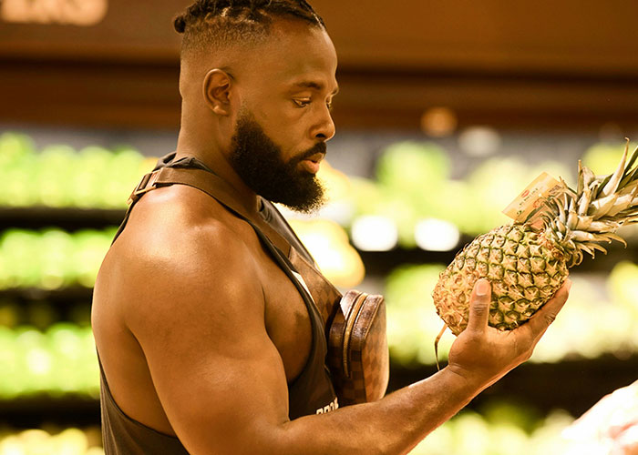 Grocery store employee inspecting a pineapple meticulously, emphasizing policy adherence. Grocery store employee inspecting a pineapple meticulously, emphasizing policy adherence.