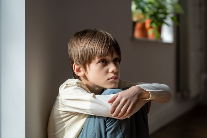 Child in light room, sitting with knees up, related to housemate mom topic. Child in light room, sitting with knees up, related to housemate mom topic.