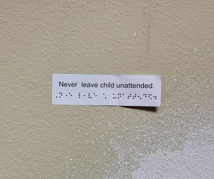 Sign on wall reads, "Never leave child unattended," with Braille misaligned, highlighting a bad day mishap.
