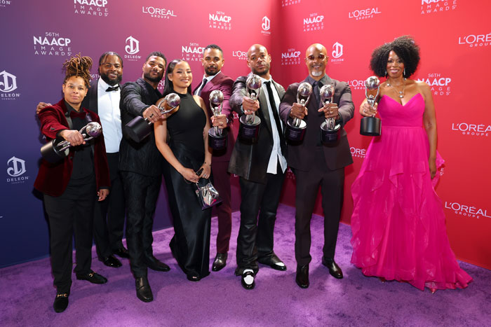 Group of film legends holding awards at the NAACP Image Awards, posing on a purple carpet. Group of film legends holding awards at the NAACP Image Awards, posing on a purple carpet.