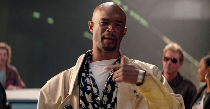 Film legend in a casual scene, wearing a beige jacket and patterned shirt, gesturing with his hand, smiling slightly. Film legend in a casual scene, wearing a beige jacket and patterned shirt, gesturing with his hand, smiling slightly.