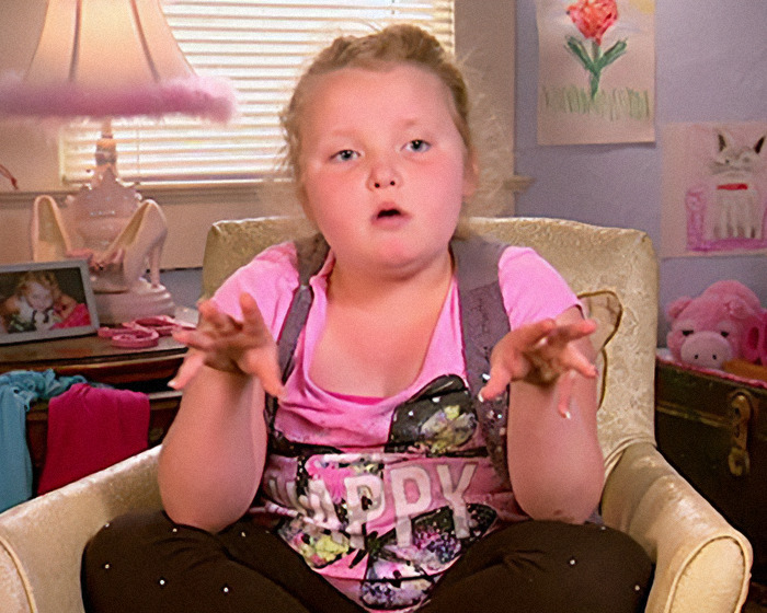 Young girl in a colorful outfit sitting in a decorated room, gesturing with hands, from Toddlers & Tiaras. Young girl in a colorful outfit sitting in a decorated room, gesturing with hands, from Toddlers & Tiaras.