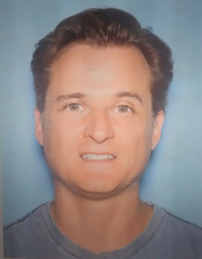 Portrait of a doctor involved in an alleged cliff incident, wearing a gray shirt against a blue background. Portrait of a doctor involved in an alleged cliff incident, wearing a gray shirt against a blue background.