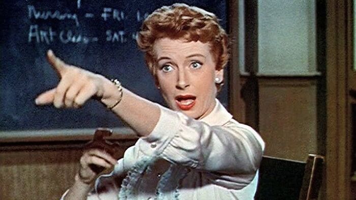 A woman emotionally gestures, evoking tears, in a dramatic movie scene.