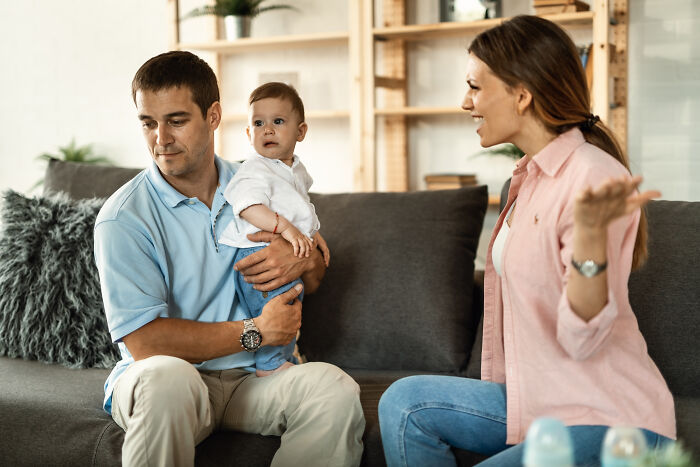A new mom arguing with husband over parenting roles while he holds their baby. A new mom arguing with husband over parenting roles while he holds their baby.