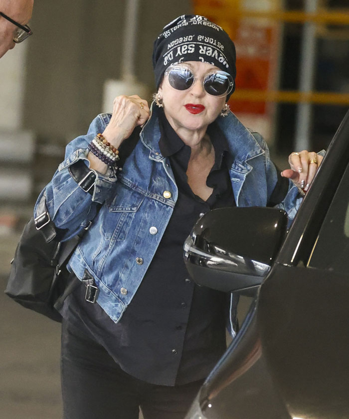 Cyndi Lauper wearing sunglasses and a denim jacket, looking unrecognizable.
