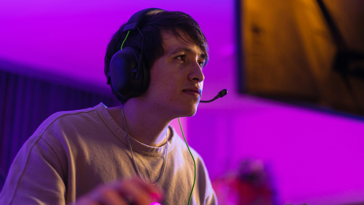 Young man wearing a headset focused on screen in a purple-lit room representing weird Quora questions concept.