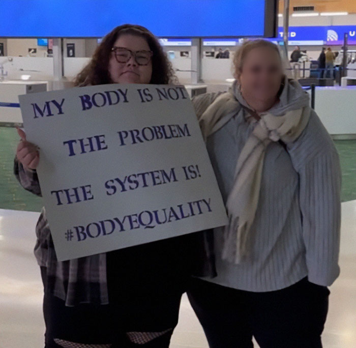 Plus-sized passenger holding sign about body equality at airport. Plus-sized passenger holding sign about body equality at airport.