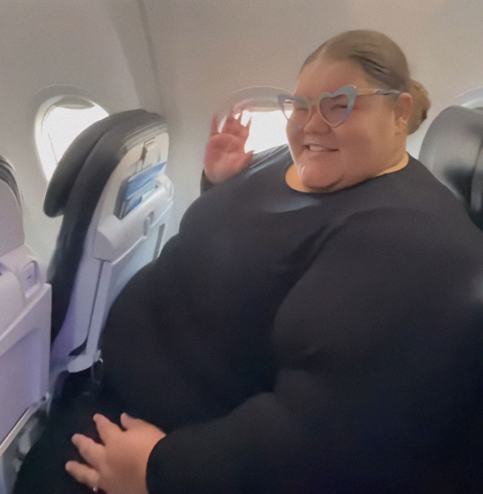 Plus-sized passenger smiling in airplane seat with heart-shaped glasses. Plus-sized passenger smiling in airplane seat with heart-shaped glasses.