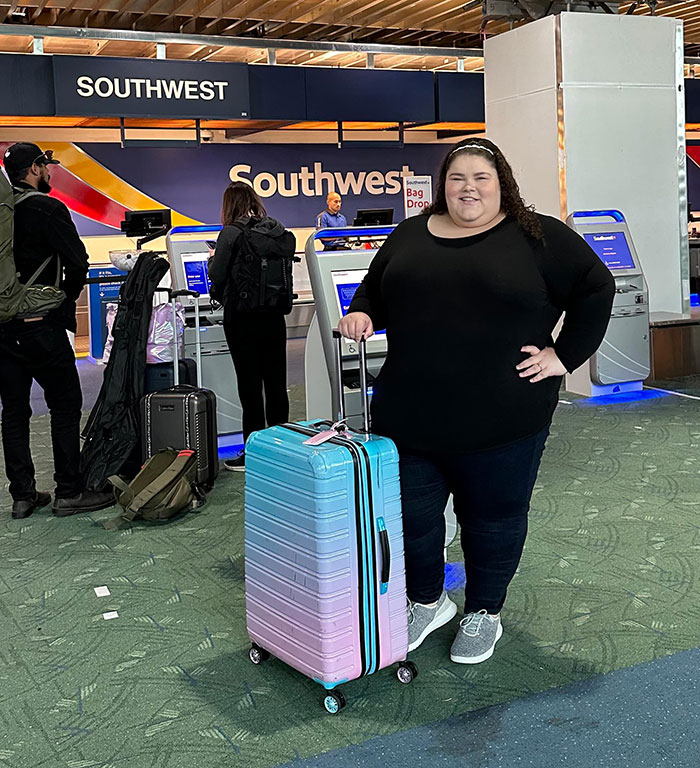 Plus-sized passenger at airport with suitcase near Southwest check-in area. Plus-sized passenger at airport with suitcase near Southwest check-in area.