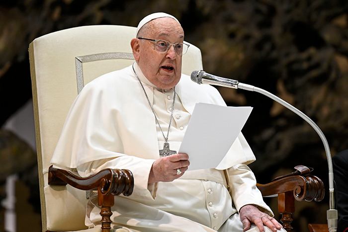 Pope Francis speaking into a microphone while holding a paper during a formal address. Pope Francis speaking into a microphone while holding a paper during a formal address.