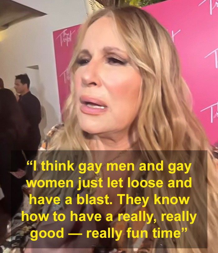 Jennifer Coolidge at an event, discussing her LGBTQ+ fans with enthusiasm, pink backdrop in background. Jennifer Coolidge at an event, discussing her LGBTQ+ fans with enthusiasm, pink backdrop in background.