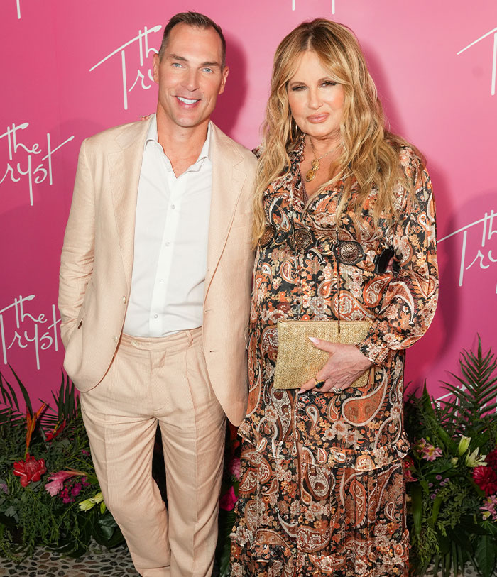 Two people posing at an event, one in a patterned dress and the other in a beige suit, highlighting LGBTQ+ fans. Two people posing at an event, one in a patterned dress and the other in a beige suit, highlighting LGBTQ+ fans.