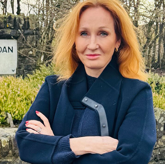 JK Rowling in a navy coat outside, arms crossed, amid spotlight controversy on toddler's school suspension. JK Rowling in a navy coat outside, arms crossed, amid spotlight controversy on toddler's school suspension.