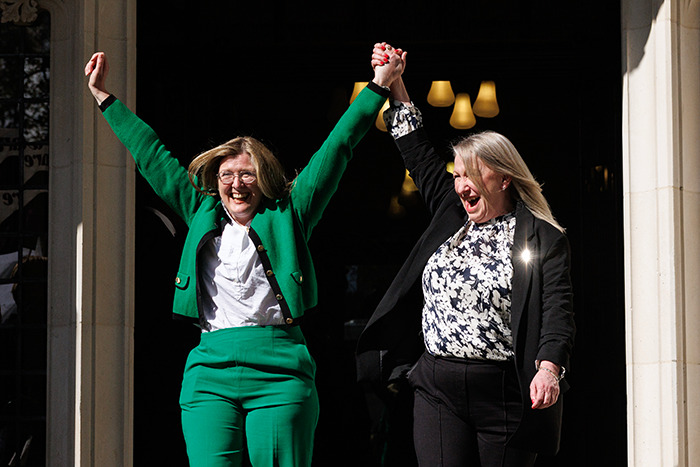 Two women celebrate with raised arms outside a building, expressing joy over a controversial Supreme Court decision. Two women celebrate with raised arms outside a building, expressing joy over a controversial Supreme Court decision.