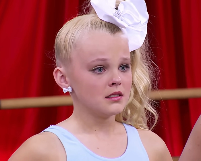 Young girl with a large white bow looking emotional, related to controversial 'Dance Moms' scenes. Young girl with a large white bow looking emotional, related to controversial 'Dance Moms' scenes.
