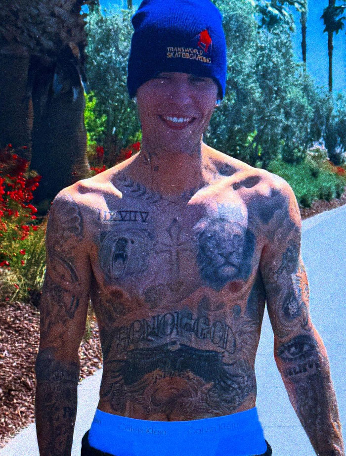 Justin Bieber outdoors, smiling in a beanie and showcasing tattoos, surrounded by greenery. Justin Bieber outdoors, smiling in a beanie and showcasing tattoos, surrounded by greenery.