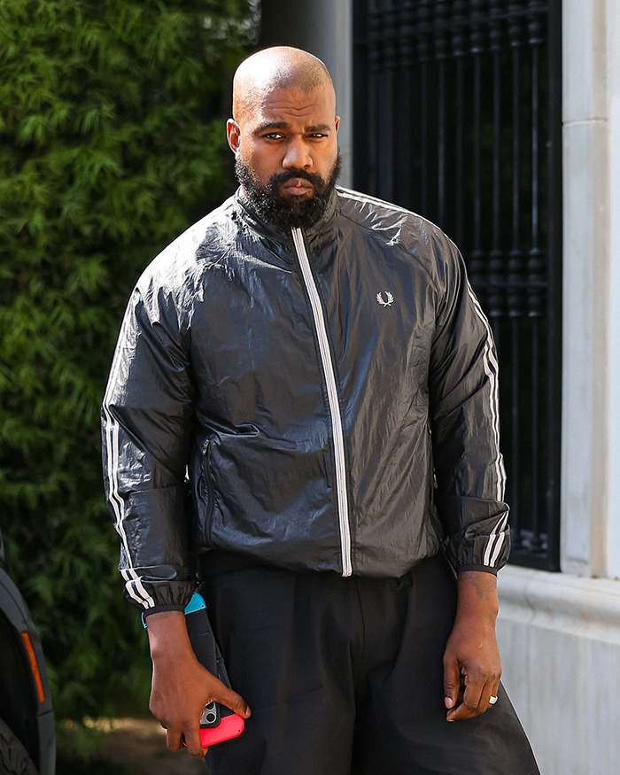 Man in black tracksuit holding phone outdoors, looking serious. Man in black tracksuit holding phone outdoors, looking serious.